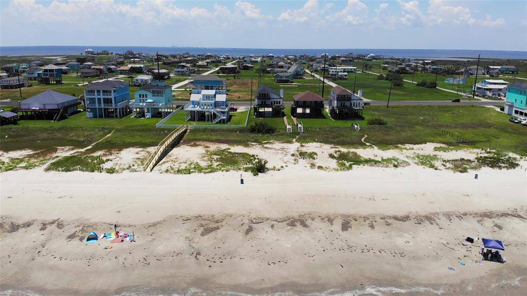 This aerial photo shows a property the beachfront home outlined in red. The lot includes a house with a clear path leading directly to the sandy shore. It's situated along a main road, providing easy access. Ideal for beach lovers seeking convenient coastal living.
