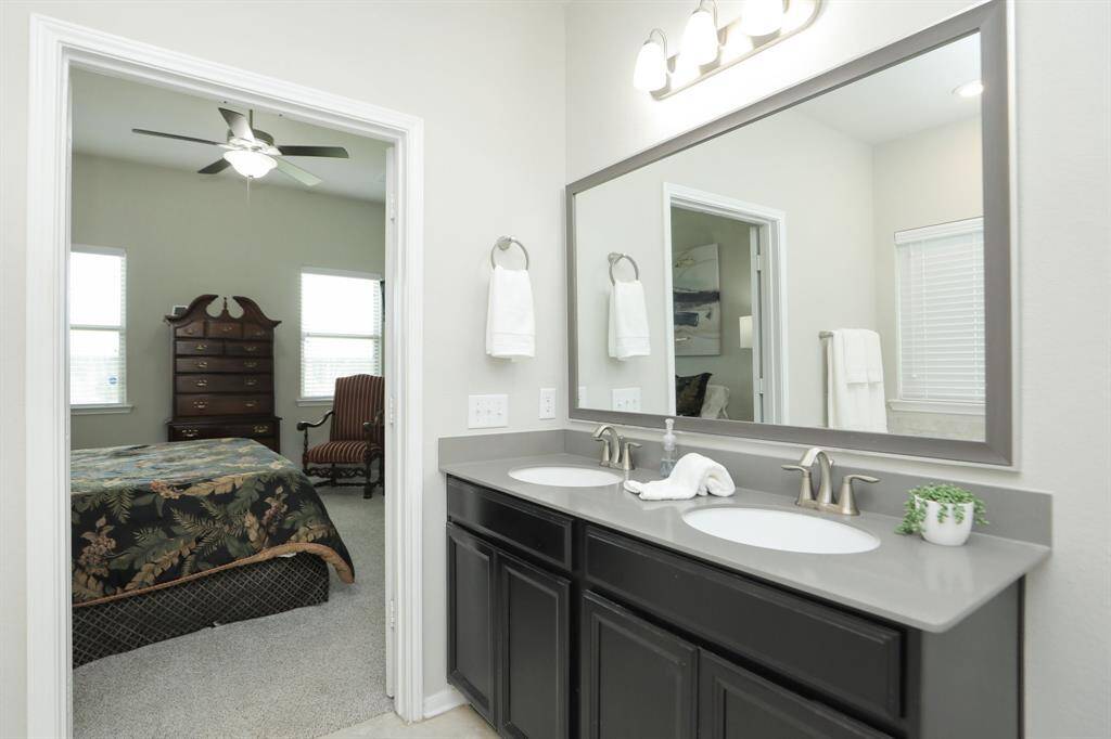 This photo shows a modern bathroom with dual sinks, sleek dark cabinetry, and a large mirror  and beautiful granite tiling.