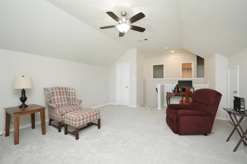 This spacious room features a cozy carpeted floor, neutral walls, and great space for a game room, media room, for office space. The room's sloped ceiling adds character and charm.
