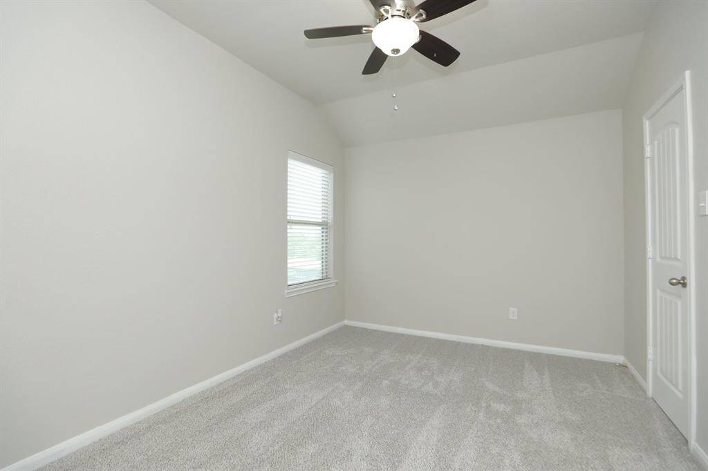 This room features neutral walls and carpet, a window with blinds, and a lighted ceiling fan.