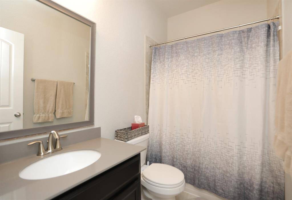 This bathroom features a modern design with a sleek vanity, a large mirror, and a shower-tub combo. Neutral tones create a clean and inviting atmosphere.