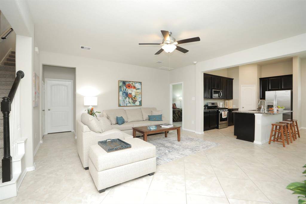 Bright, open-concept living area with neutral tones and great tile flooring.Stairs lead to the upper level, creating a welcoming and functional space.