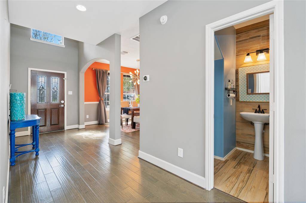 This inviting home features a bright entryway with wood flooring, leading to a colorful dining area. A stylish powder room is conveniently located near the entrance.