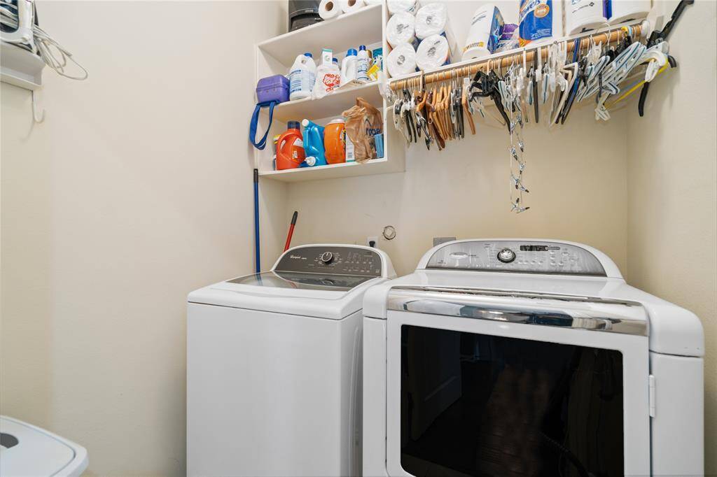 This laundry room features a washer and dryer set, ample shelving for storage, and a hanging rod for clothes. It's compact yet functional, ideal for efficient laundry tasks.