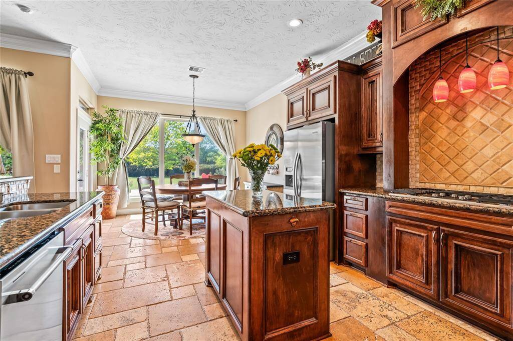 CHEF'S KITCHEN FEATURES A 5-BURNER GAS COOKTOP, STAINLESS STEEL APPLIANCES, AND CUSTOM CABINETRY.