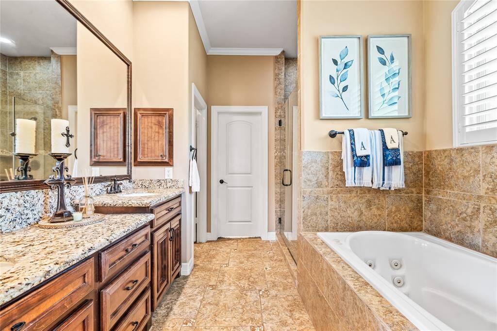 PRIMARY BATHROOM BOASTS A TWO-TIERED VANITY AREA WITH GRANITE COUNTERTOPS AND PLENTY OF STORAGE