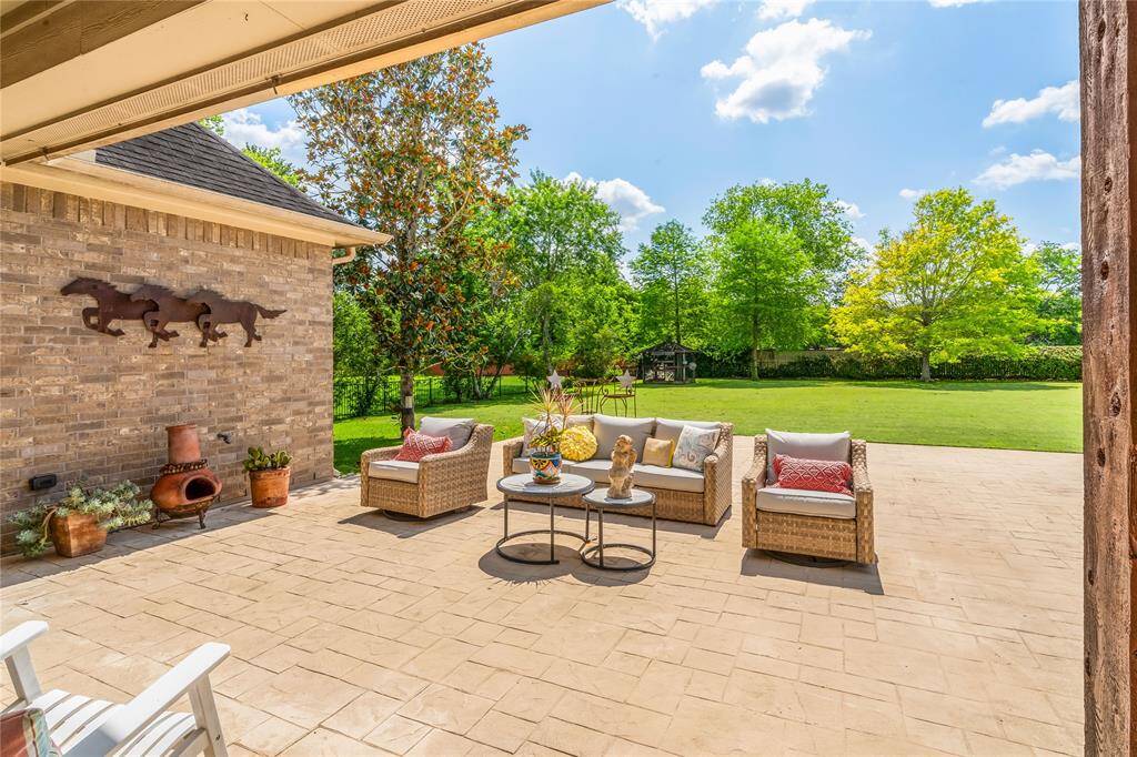 BACK PATIO DESIGNED FOR RELAXING AND ENTERTAINING, FEATURING STAMPED CONCRETE AND LOUNGE SEATING.