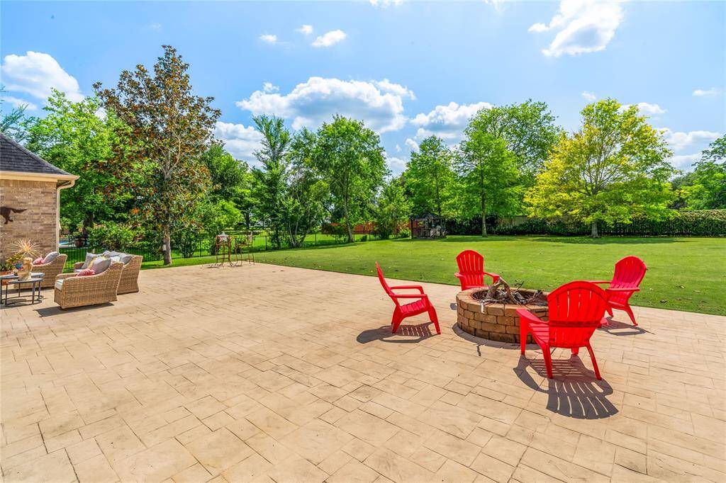 SPACIOUS BACKYARD WITH A BUILT-IN FIREPIT, MATURE TREES, AND PLENTY OF ROOM TO ROAM OR PLAY.
