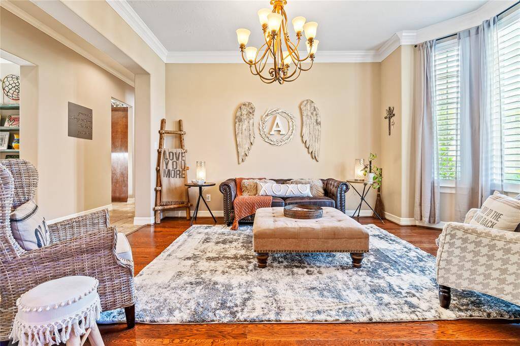 SPACIOUS LIVING ROOM WITH ELEGANT CROWN MOLDING AND RICH WOOD FLOORING FOR A REFINED FIRST IMPRESSION.