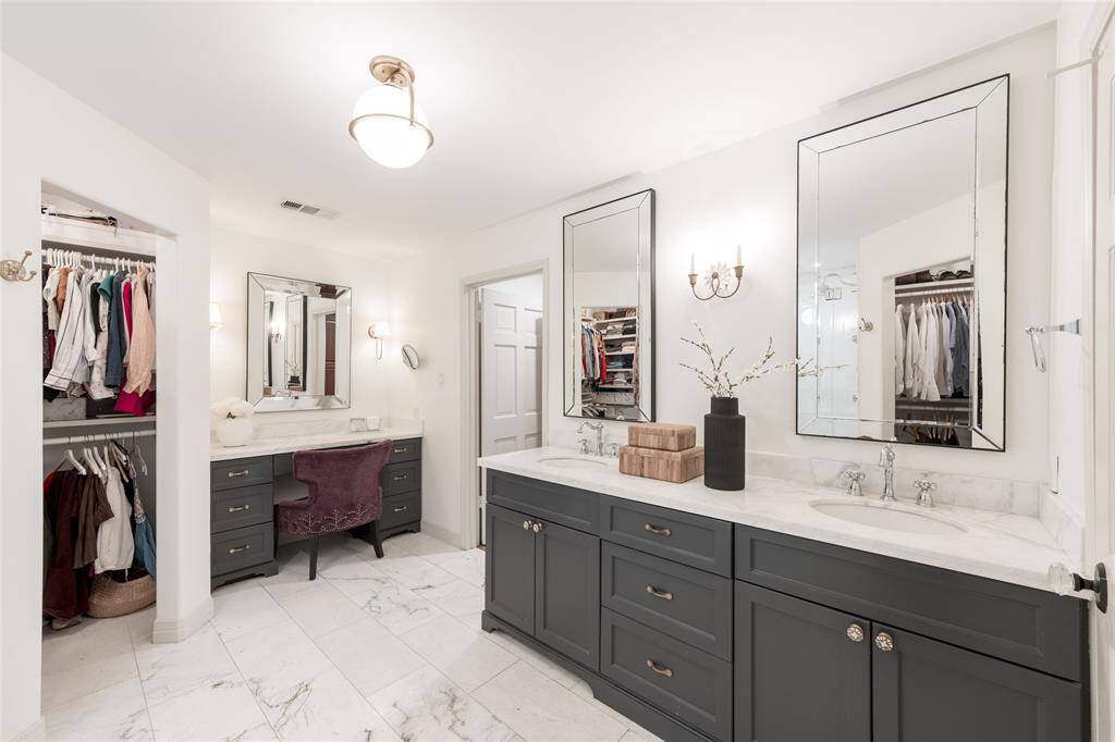 Primary en-suite bathroom includes a large walk in shower, two closets, and a vanity area.