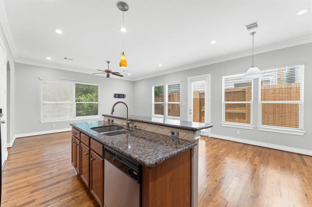 This spacious kitchen features a large island with granite countertops and stainless steel appliances. The open layout includes hardwood floors, ample natural light from multiple windows, and modern pendant lighting. Ideal for entertaining and family gatherings.