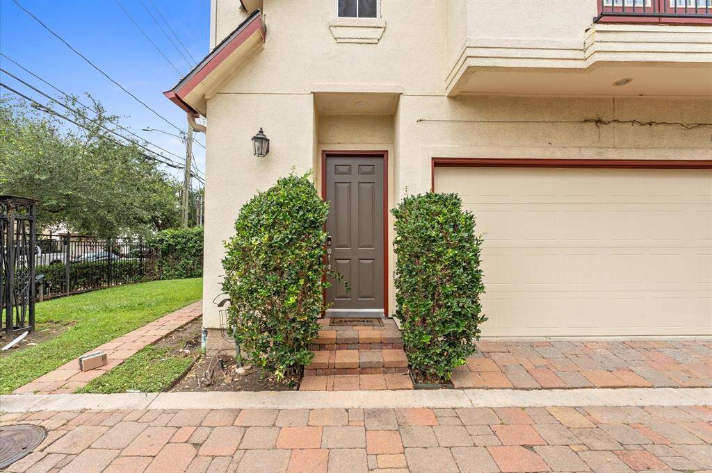 This home features a charming entrance with a neatly paved walkway, flanked by manicured shrubs. The exterior is well-maintained, offering a modern look with a neutral color palette. The adjacent garage adds convenience and functionality.