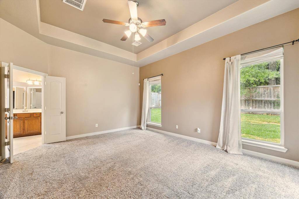 Unwind in this spacious Master Bedroom suite featuring tray ceilings, plush neutral-toned carpet. French doors lead to a private en-suite bath, creating a peaceful retreat to start and end your day.