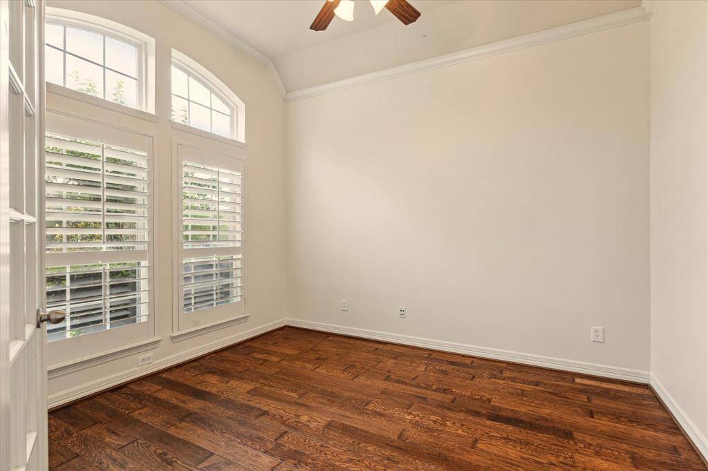 Work in style and comfort in this dedicated home office featuring elegant French doors, oversized windows that pour in natural light, and soaring high ceilings that add an open, airy feel. The perfect space for productivity or quiet reflection.