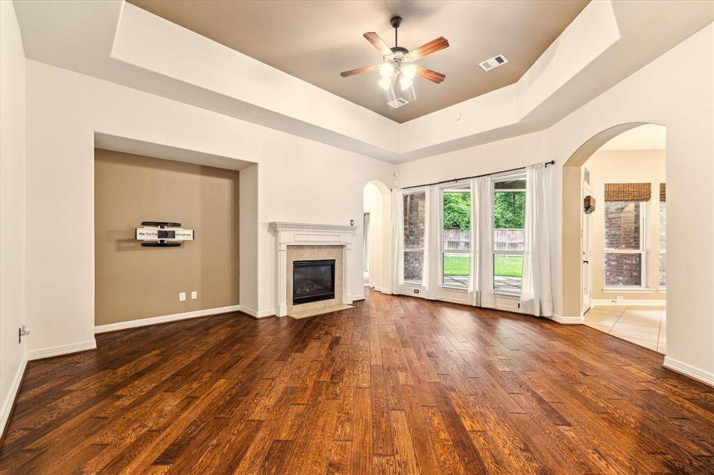 Spacious and inviting, this family room features rich hardwood floors, a cozy gas fireplace, tray ceilings with crown molding.