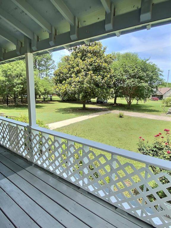 Charming, covered, wraparound porch with lattice railing, overlooking a lush, green yard. Perfect for relaxing outdoors.