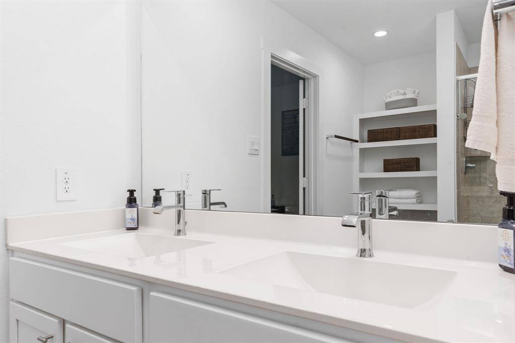 Primary en-suite bath with dual vanity sinks and standing shower.