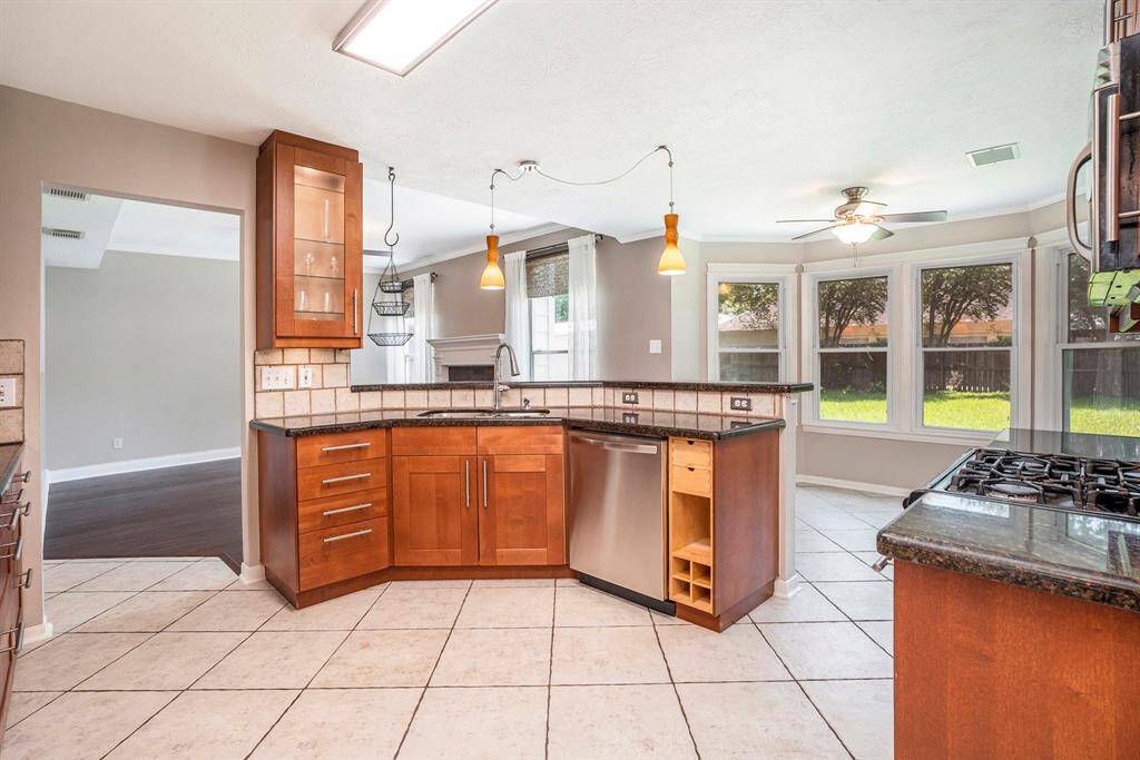 This view from the kitchen highlights the open concept layout, with clear sightlines to the living room, breakfast area, and backyard. Ample natural light and warm finishes make it feel bright and connected.
