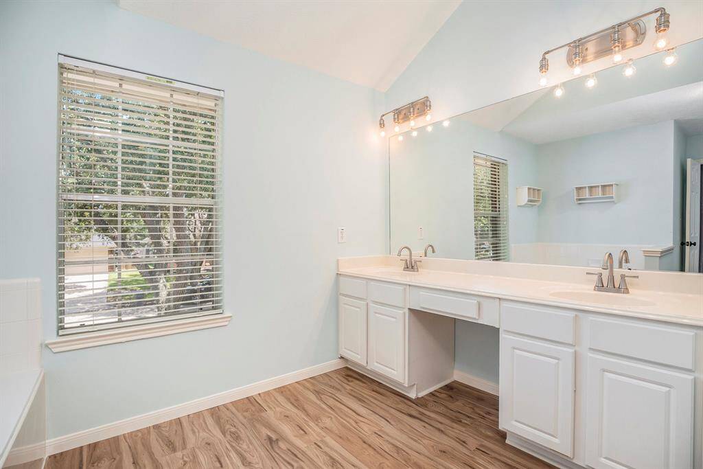 The primary bathroom offers a bright, open layout with double sinks, a large mirror, and updated lighting. Tile flooring adds durability and style, while the spacious vanity provides plenty of counter space and storage.