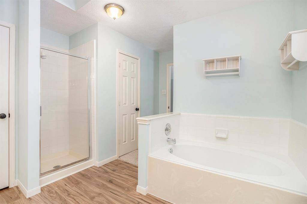 The primary bathroom includes a relaxing soaking tub, separate shower, and durable tile flooring. It offers a spacious layout with both function and comfort in mind.