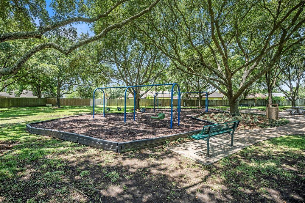 This shaded park area features swings, benches, and walking paths under a canopy of mature trees—an inviting spot for outdoor activity and relaxation.