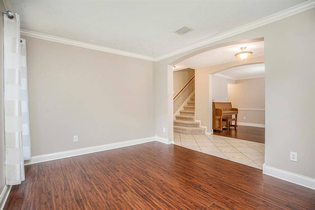 The formal living room features warm wood-look flooring, soft natural light, and neutral tones—perfect for a sitting area or flexible space just off the entry.
