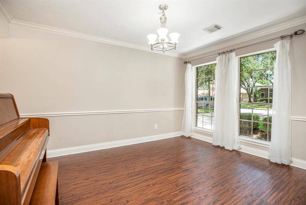 The formal dining room offers wood-look flooring, crown molding, and a large front-facing window that fills the space with natural light—an ideal setting for gatherings and meals.