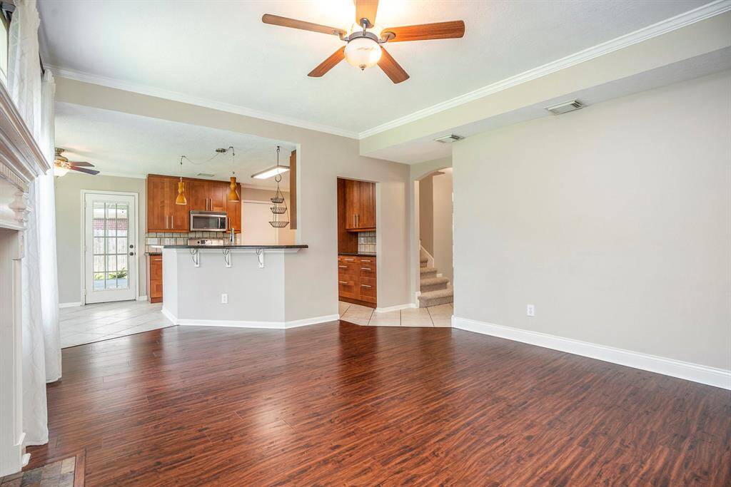 The open layout connects the living room to the kitchen, with bar seating and a view of the warm wood cabinetry and stainless appliances. Perfect for everyday living and entertaining.