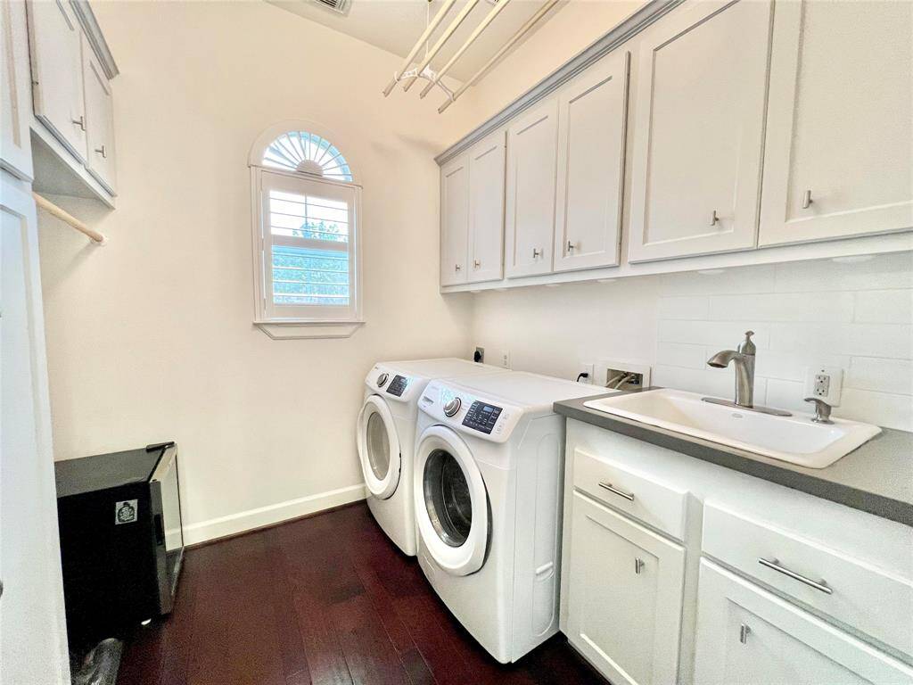 The utility room offers many cabinets and a countertop and sink.