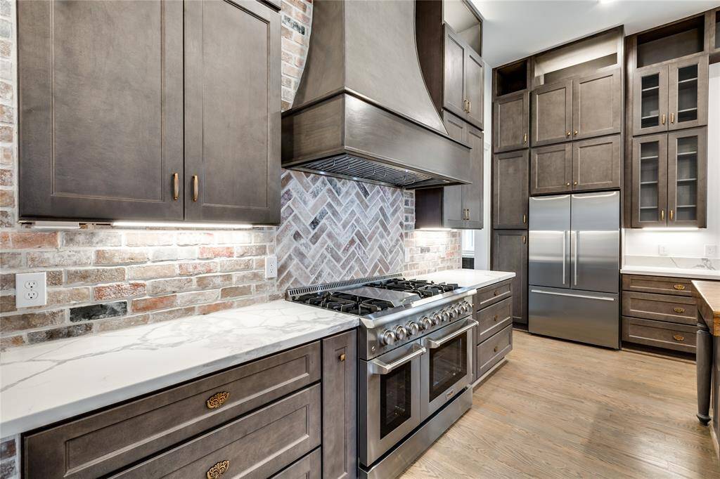 stainless steel appliances, double oven, range, custom hood, decorative brick wall
