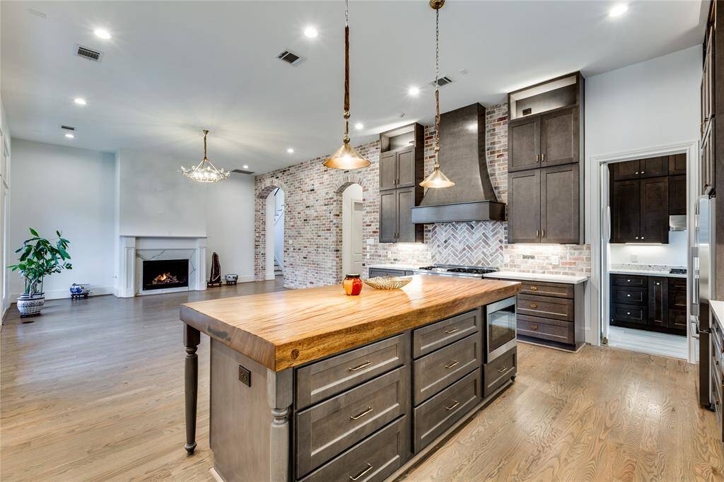 view from kitchen to living room and dirty kitchen with lots of cabinet storage, fireplace in living room with stone accent