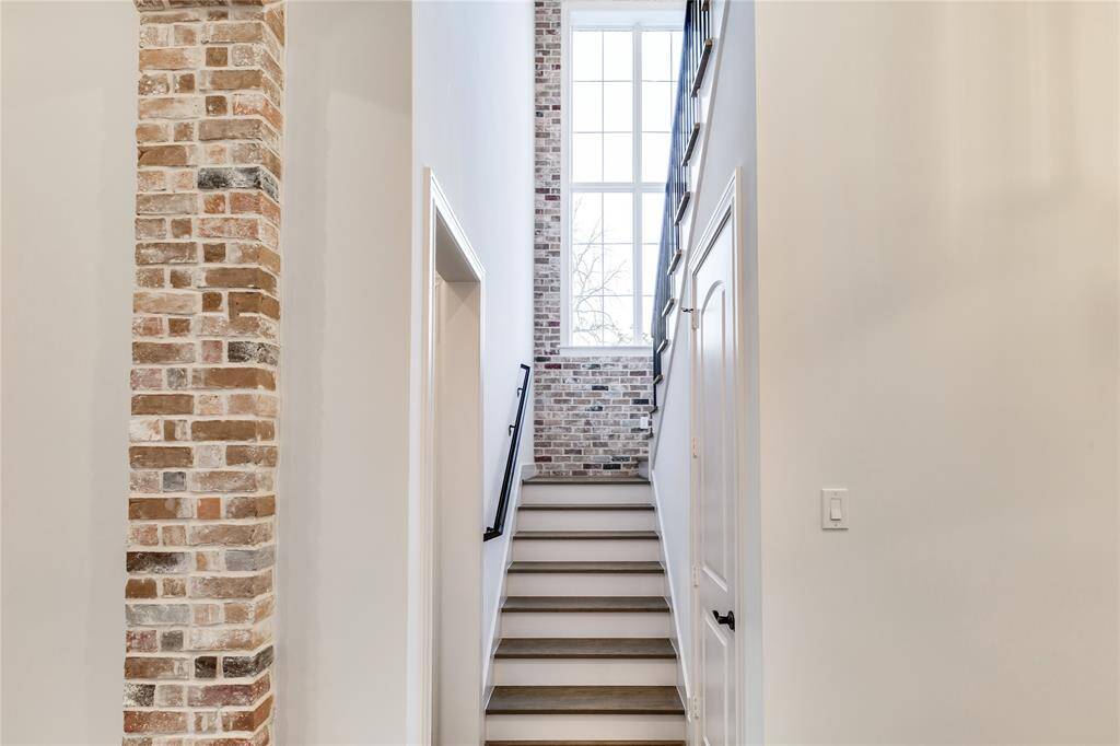 great staircase with hand-hammered steel bars imported from Italy, and notice the big and tall window and brick accent!