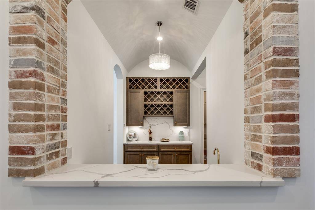 Wine bar with barrel ceiling and brick accent, stone countertop, crystal chandelier
