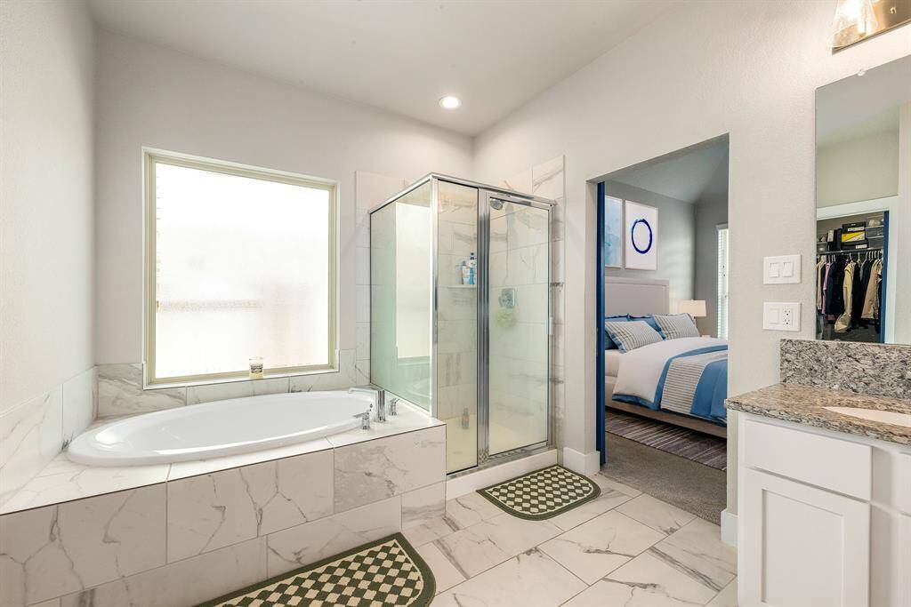 This additional view of the primary bath showcases a walk-in shower with tile surround and a separate garden tub perfect for soaking after a long day.