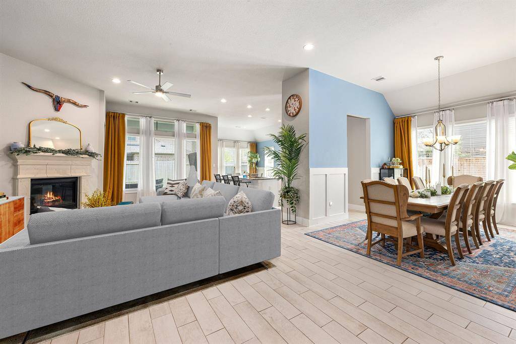 This living room is more like a GREAT room featuring a stunning fireplace with mantel detailing, custom paint, soaring high ceiling, recessed lighting, dark stained ceiling fan, and an amazing wall of windows providing a lovely view of your backyard to keep an eye out on the kids or pets playing. *Virtually Staged