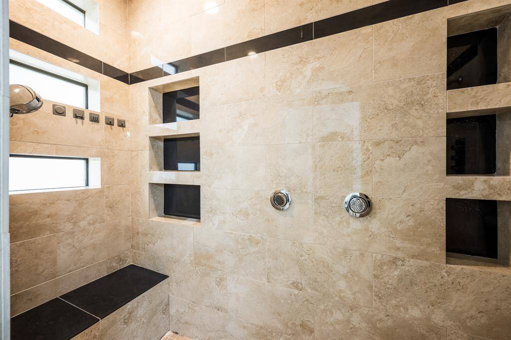 Marble walk-in shower complete with sister shower heads and a rainfall shower head. This wet room features a small bench as well.