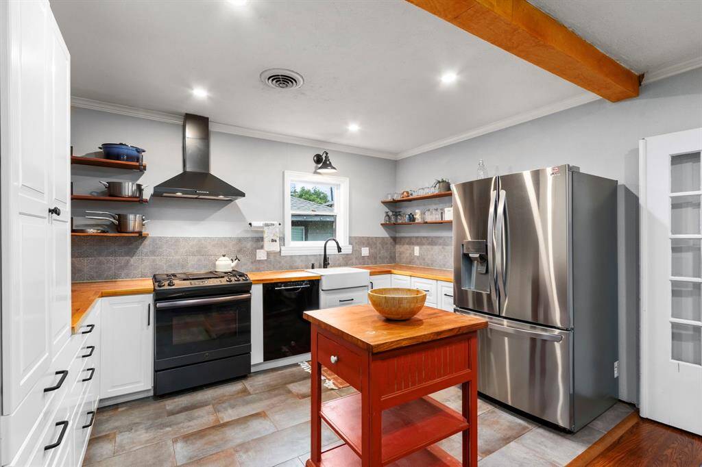 Updated rectangular tile flooring combines neutral warm and cool tones to coordinate with any color palette. The mobile island provides additional prep and serving space, and will convey with the home. A farmhouse sink, gas range with stainless steel vent hood are both attractive and functional. Dual lazy Susans and a combination of cabinets, open shelving, and drawers optimize storage.