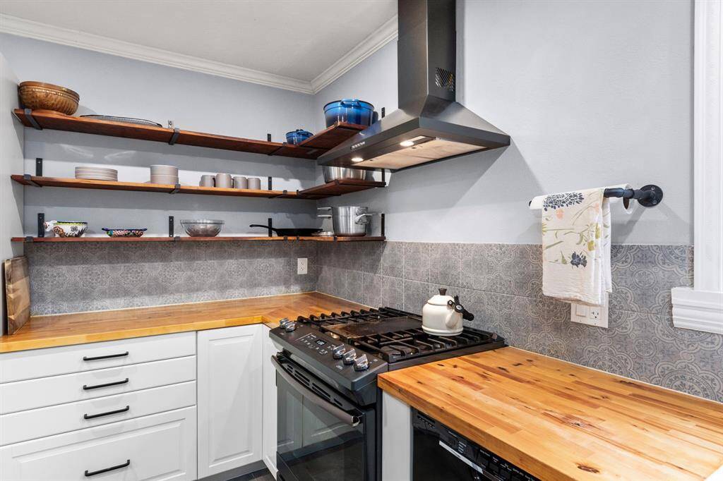 Abundant storage solutions make this a highly functional and efficient kitchen. Butcher block countertops were selected for their timeless visual appeal and in keeping with the historic nature of the home. A subtly patterned backsplash adds dimension to this utilitarian space within the home.