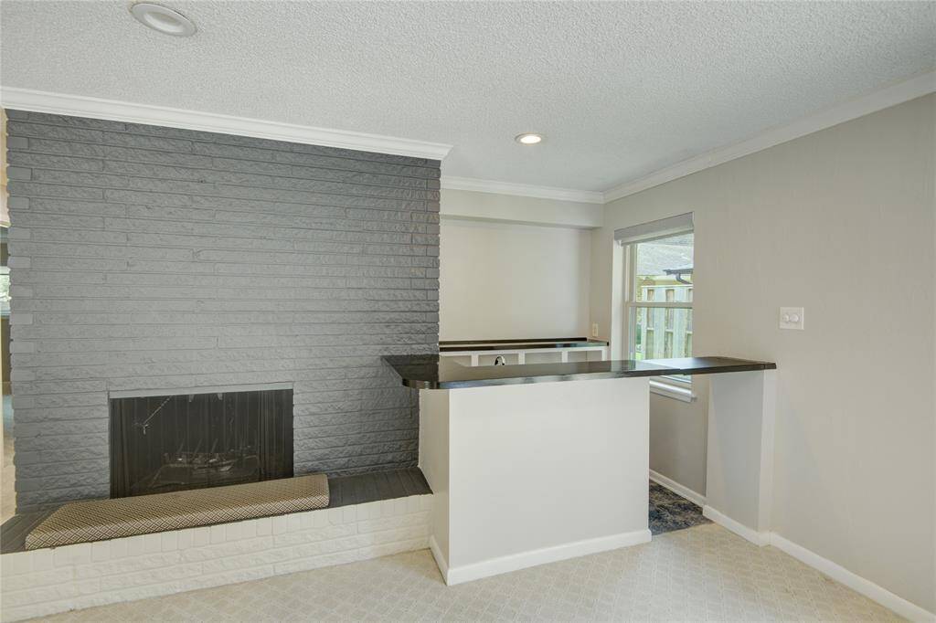This elegant corner of the family room showcases a sleek wet bar and a statement fireplace.