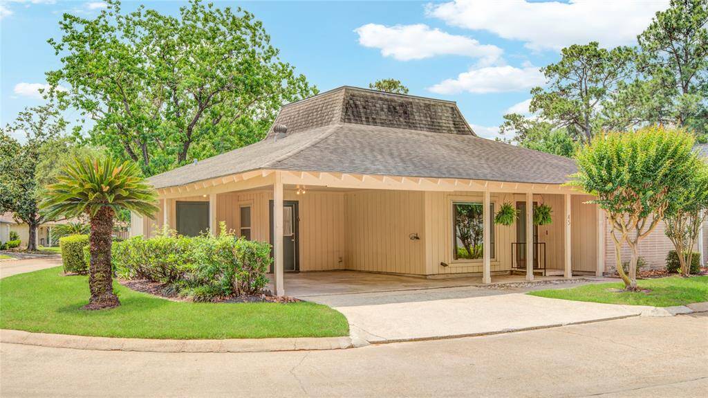 A closer look at the home highlights the covered carport, mature landscaping, and inviting front entry.