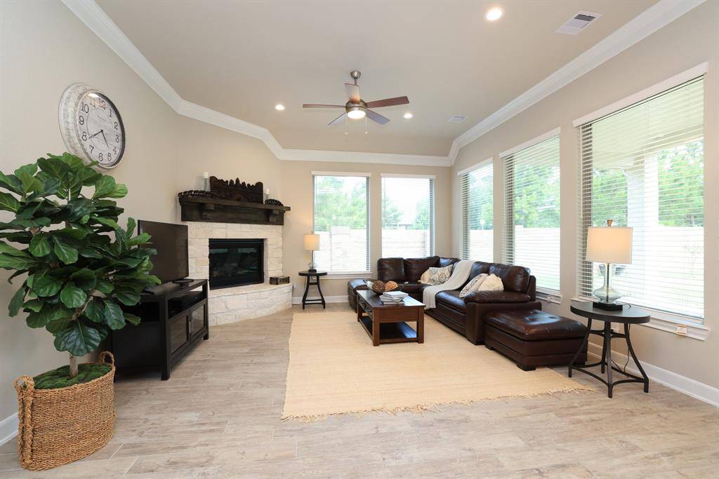 The open-concept living area is perfect for everyday comfort and entertaining, with the fireplace serving as a stunning centerpiece. Crown molding and abundant natural light enhance the warmth and elegance of the space.