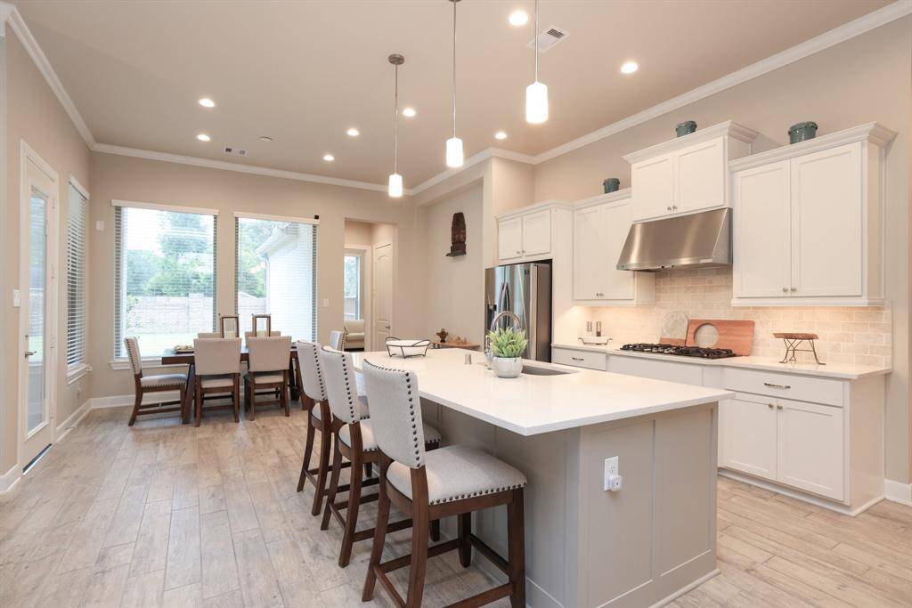The kitchen is beautifully appointed with sleek quartz countertops, stainless steel appliances, under-cabinet lighting, gas cooking, and stylish cabinet hardware, offering both function and modern elegance.