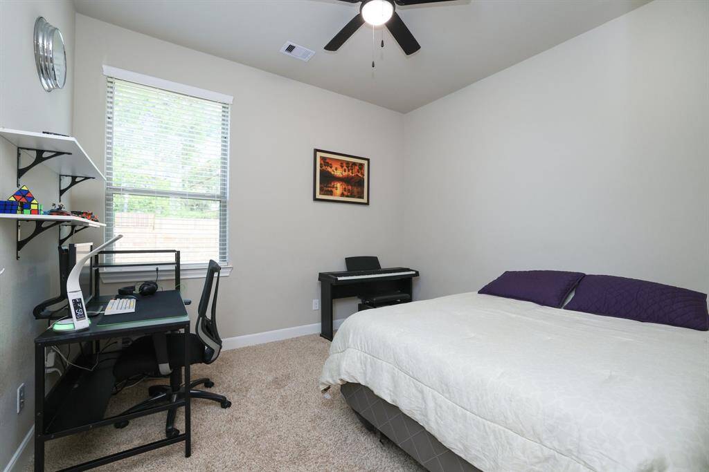One of the two secondary bedrooms features comfortable carpeting, nicely sized closet, and a ceiling fan, ensuring a cozy and functional space.