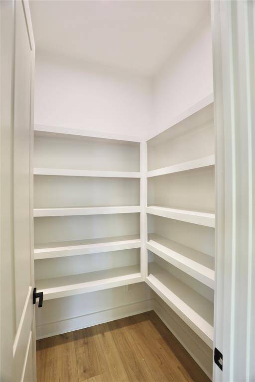 walk-in pantry, featuring built-in shelving, is conveniently located within the kitchen for optimal accessibility and storage.