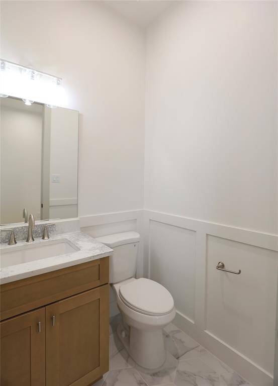 The first-floor powder room exudes charm and dimension, featuring exquisite carpentry with partial wainscoting, elegant hexagon tile flooring, and a designer faucet that adds a refined touch.