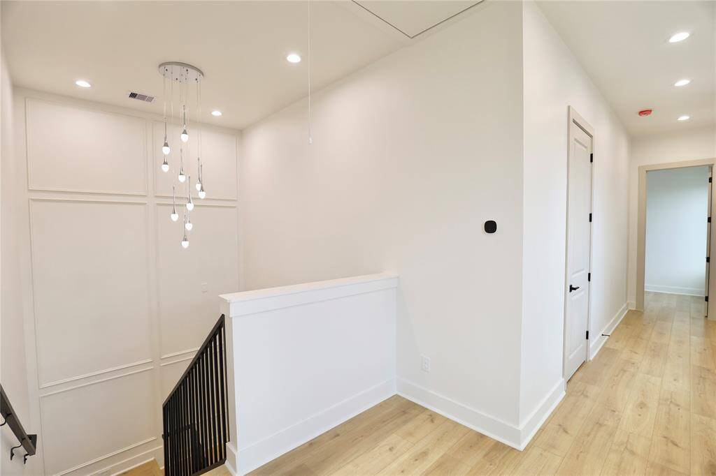 Comfort and control are elevated with dual-zone climate control—note the smart thermostat. The primary suite awaits through the door on the right side of the home, while the remaining bedrooms are thoughtfully placed on the opposite side for added privacy.