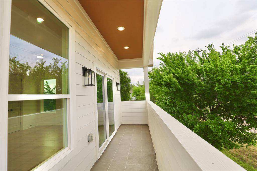 Primary private balcony with sliding door and cedar ceilings, lush mature trees around the area. Perfect to set up a patio set.