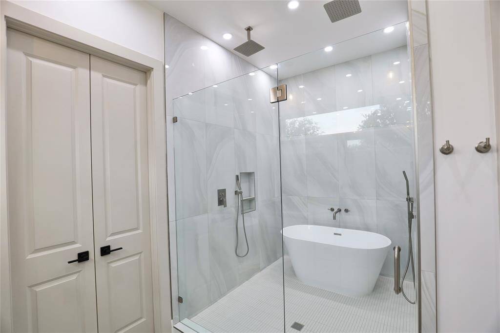 Two designer towel hooks, finished to match the faucets, beautifully complement the wide glass shower door, creating a cohesive, modern look.