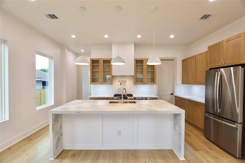 The specialty imported leather island, featuring a stunning waterfall edge, pairs beautifully with the exquisite carpentry beneath, where your barstools will sit, and thick quartz countertops—creating a truly captivating focal point