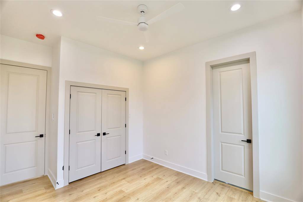 Second bedroom offers a white ceiling fan with a wall mounted remote, two French doors open to your closet.